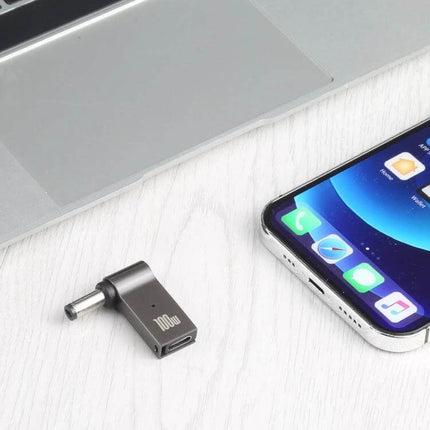 USB-C to DC Charging Adapter for Laptops and Portable Devices shown beside a laptop and smartphone for travel and on-the-go charging