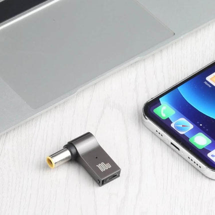 100W USB-C to DC Charging Adapter for Lenovo Laptops shown next to a laptop and smartphone for travel charging
