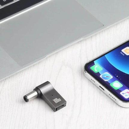 100W USB-C to DC Charging Adapter for Dell Devices pictured next to laptop and smartphone, compact travel charging solution
