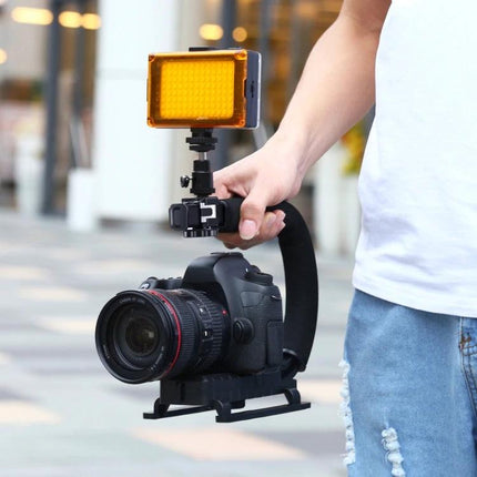 PULUZ Handheld Camera Stabilizer with Portable LED Light Kit held by vlogger capturing steady, well-lit outdoor footage