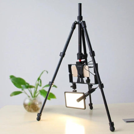 PULUZ Metal Tripod with Adjustable Height for Cameras set up on table holding phone and LED light for indoor shooting