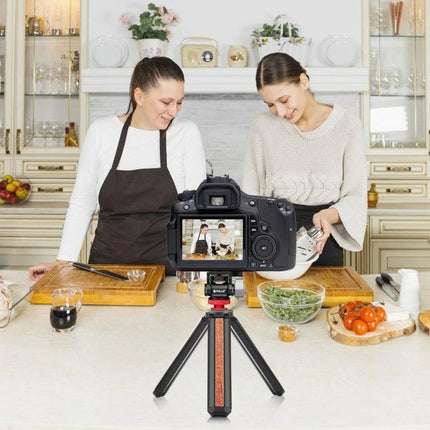 PULUZ Mini 180 Degree Adjustable Tripod Ball Head for Cameras mounted on small tripod filming two women cooking in kitchen