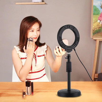 PULUZ 4.7 Inch Dimmable LED Ring Light for Video and Vlogging illuminating woman applying makeup with compact mirror on tabletop