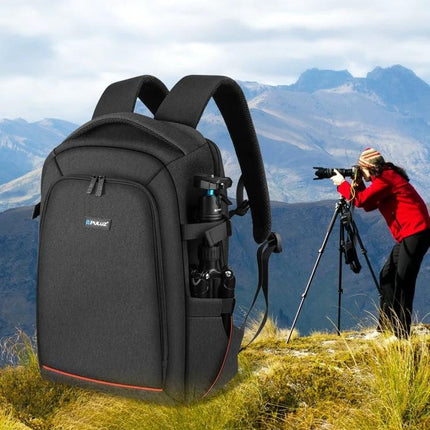 PULUZ Outdoor Waterproof Backpack for Cameras and Accessories shown on a mountain trail with DSLR, lenses and tripod — organized, padded camera travel bag