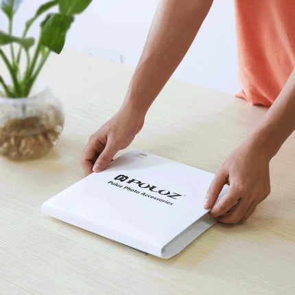 PULUZ Portable Folding Light Box for Small Item Photography being unfolded on a table by hands, compact white portable studio