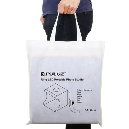 PULUZ 30cm Folding Light Box Kit for Small Product Photography carrying bag held by person, portable foldable photo studio
