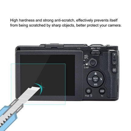 PULUZ 9H Tempered Glass Screen Protector for Digital Cameras shown on camera rear screen resisting a craft knife scratch