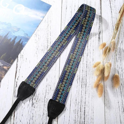 PULUZ Retro Ethnic Style Camera Strap for DSLR Cameras showing colorful woven vintage pattern and black leather ends on white wooden background