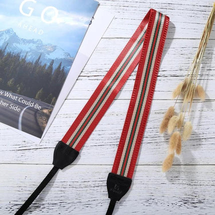 PULUZ Vintage Stripe Camera Neck Strap for SLR Cameras laid flat on white wood surface with red, green and white stripes