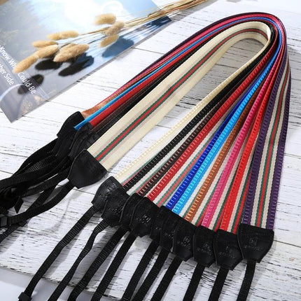 PULUZ Vintage Stripe Camera Neck Strap for SLR Cameras showing multicolor striped cloth straps with leather ends laid out on a wooden surface
