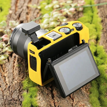 PULUZ Soft Silicone Protective Case for Canon EOS M3 shown on yellow-covered camera with flip-out LCD on mossy log