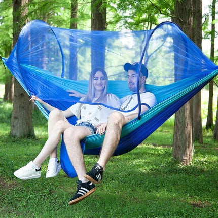 Portable Outdoor Camping Nylon Parachute Hammock 250x120cm with built-in mosquito net shown in blue hanging between trees with couple relaxing