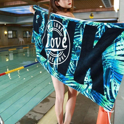 Printed Soft Bath Towel 147x71 cm For Home And Beach shown draped by a pool with tropical blue leaf print and ‘love’ circle design