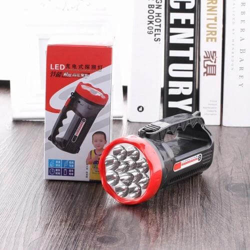 Rechargeable Outdoor LED Flashlight With Two Modes displayed on wooden table with packaging and multiple LED bulbs, portable handle and red bezel