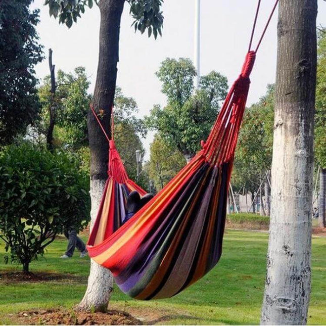 Red Stripe Canvas Hammock 190x100cm Camping Outdoors hanging between trees in a park for backyard or campsite relaxation