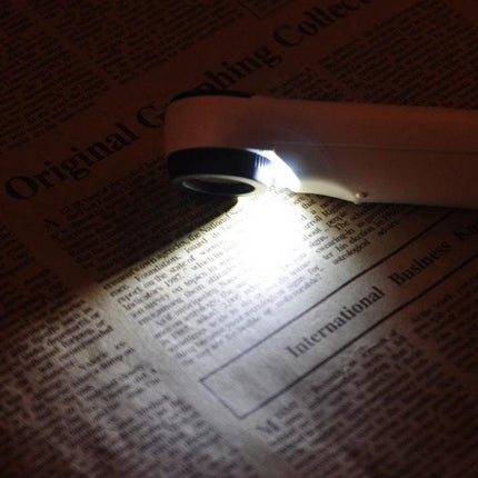Handheld 40X Magnifier with LED Light for Everyday Reading showing LED illumination on newspaper for reading fine print