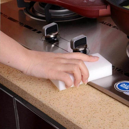 High-Density Nanometer Cleaning Sponge for Everyday Home Surfaces being used to wipe a stovetop edge with water only, hands holding the sponge