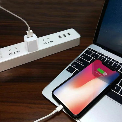 A USB Charger for Daily Device Powering at Home and Travel plugged into wall outlet charging smartphone on laptop for home and travel use