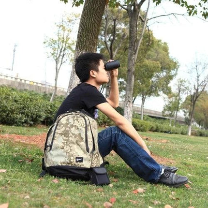 Handheld Waterproof Rangefinder for Golf and Outdoors used by a hiker sitting on grass checking distance with binocular-style device