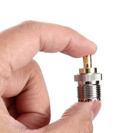 SMA Female to UHF Female Coaxial Adapter for Antenna Connections held between fingers showing connector detail