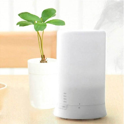 Mini USB Aroma Diffuser With Warm White LED Lights on desk releasing mist with warm white glow and small plant nearby