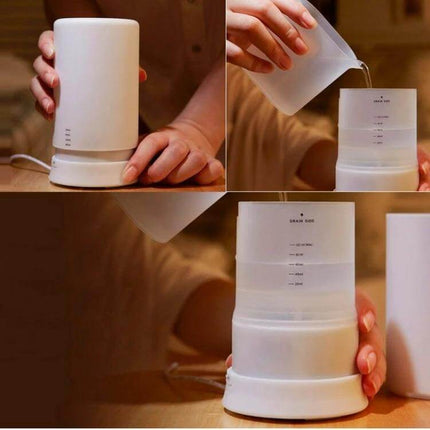 Mini USB Aroma Diffuser With Warm White LED Lights compact white diffuser on desk pouring water into 70ml tank, USB powered, gentle warm LED glow