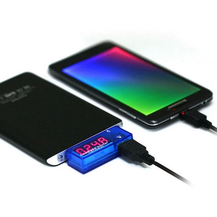 Portable USB Current and Voltage Tester for Mobile Chargers showing digital readout between power bank and smartphone
