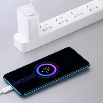 Xiaomi USB Charger for Everyday Device Use at Home powering smartphone with 33W fast charging connected to white power strip