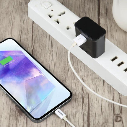 Essential Travel Adapter for Daily Device Charging plugged into power strip charging a smartphone with compact black adapter and USB cable