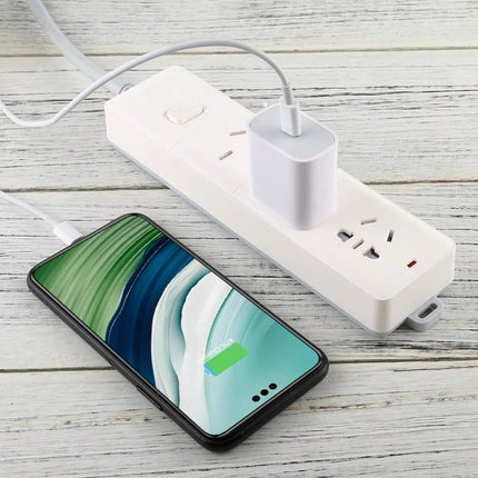 Compact Power Adapter for Travel and Daily Charging Needs plugged into power strip charging smartphone on wooden desk