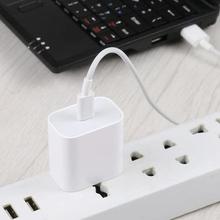 Compact USB-C Adapter for Daily Device Charging at Home plugged into power strip charging a laptop and smartphone