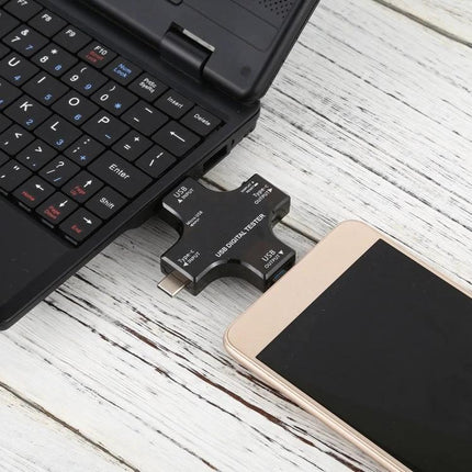 Multifunctional USB Safety Tester for Monitoring Charging Devices plugged between laptop and smartphone to measure voltage and current