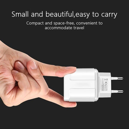 Travel Charger and USB Cable for Everyday Device Powering — compact dual USB wall charger shown between fingers for easy travel