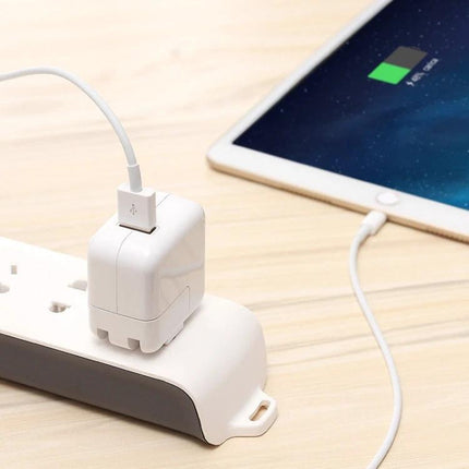 Compact USB Charger for Everyday Device Use at Home plugged into power strip charging a tablet on a wooden desk