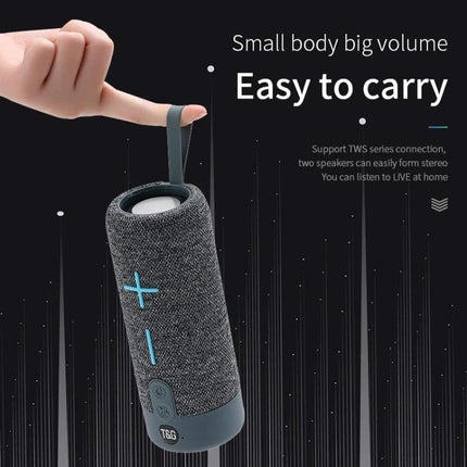 TG Portable Waterproof Bluetooth Speaker For Travel And Beach Use shown hanging by strap, portable gray cylindrical speaker