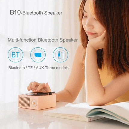 X10 Compact Retro Bluetooth Speaker With Rose Gold Dial on desk with woman, vinyl-style rotating disc and rose gold dial