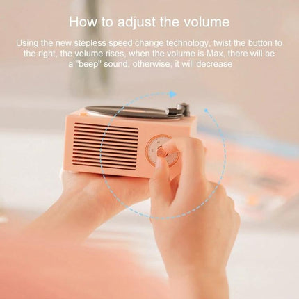X10 Compact Retro Bluetooth Speaker With Rose Gold Dial shown on desk being held while user adjusts the rose gold volume dial