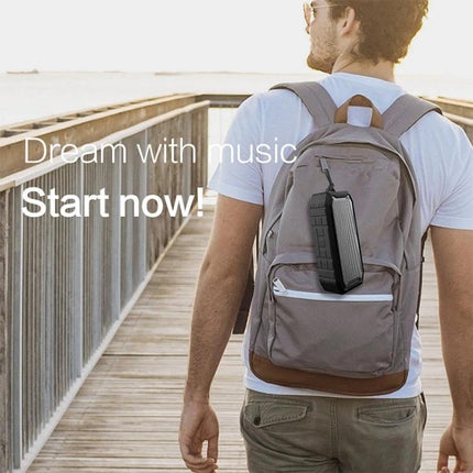 Portable Bluetooth Travel Speaker With Detachable Strap clipped to backpack on pier for hands-free outdoor listening