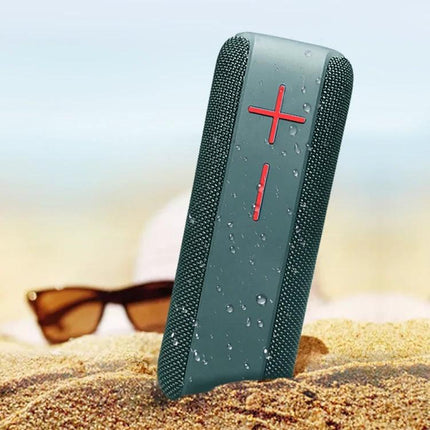 Portable Bluetooth Speaker With Carabiner For Outdoor Use shown wet on sandy beach with sunglasses, clipped-ready rugged design