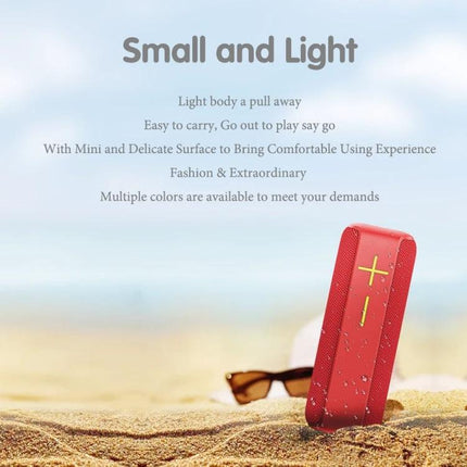 Portable Bluetooth Speaker With Carabiner For Outdoor Use shown red on sandy beach with sunglasses, small and light, water-resistant design