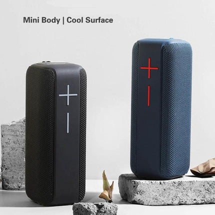 Portable Bluetooth Speaker With Carabiner For Outdoor Use shown clipped to a backpack and placed on a picnic surface