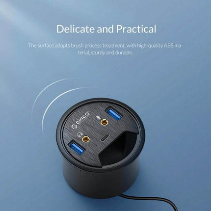 Orico Desktop Multi-Function Hub with USB and Audio Ports on desk showing dual USB and audio ports, round black brushed top for home office