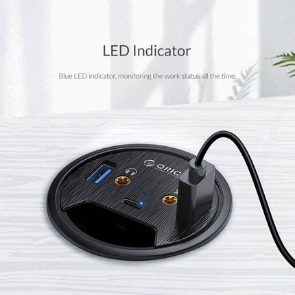 Orico Desktop Multi-Function Hub with USB and Audio Ports shown with LED indicator, USB-A port and audio jacks on a desk