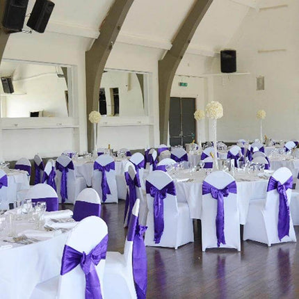 Satin Chair Bows 3-Piece Set, 14 cm x 275 cm for Weddings tied in purple satin on white chair covers at a wedding reception