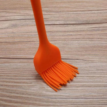 Silicone BBQ Oil Brush For Easy Basting Of Grilled Foods orange silicone basting brush on wooden surface