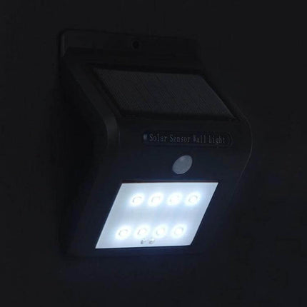 Solar Motion Sensor Wall Light For Outdoors With 8 LEDs mounted on wall at night showing illuminated 8 LEDs and solar panel