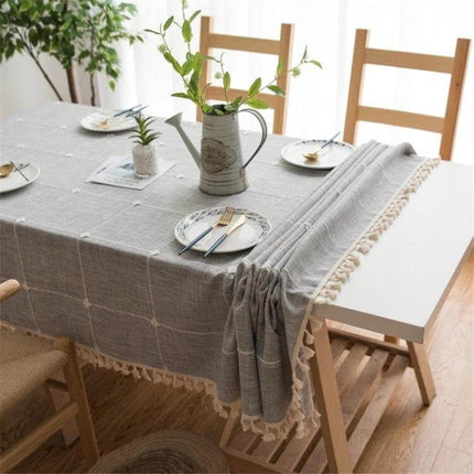 Square Lattice Embroidered Tablecloth, Tassel Border draped on dining table with neutral linen-style cotton, dyed stripe detail and tasseled edge