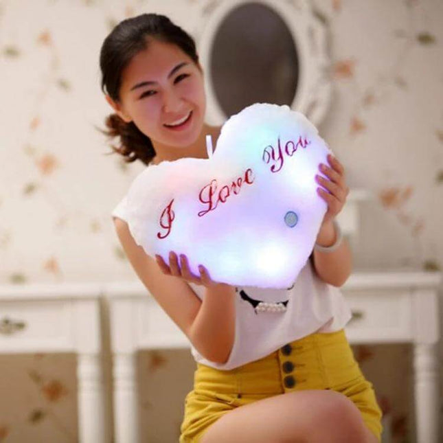 Heart Shaped English Letter Pattern Glowing Plush Pillow held by smiling woman, soft PP cotton, glowing I Love You design for sofa, parties, storefront displays