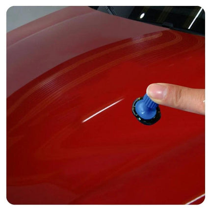 Versatile Suction Cups for Everyday Car Maintenance at Home - finger placing blue suction cup on small dent of red car hood for DIY repair