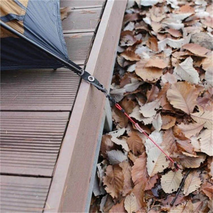 Outdoor Tent Elastic Rope Buckle For Secure Camping attached to tent guy line and deck edge securing tarp in leaf-strewn campsite